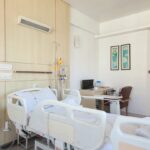 A hospital room with empty beds and medical equipment, depicting a healthcare environment.
