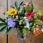 A beautiful arrangement of fresh flowers including sunflowers, daisies, and colorful blooms in a natural setting